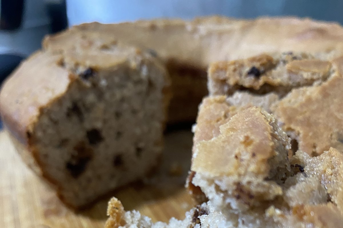 Queque de yogur y chocolate sobre una tabla de madera, con un trozo ya cortado